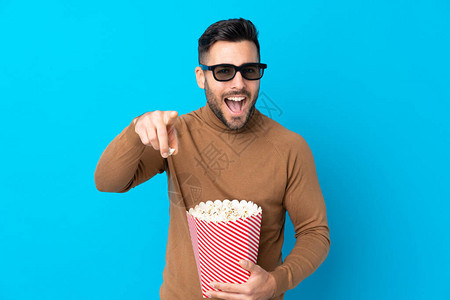 英俊的年轻人拿着3D眼镜拿着一桶大爆米花背景图片