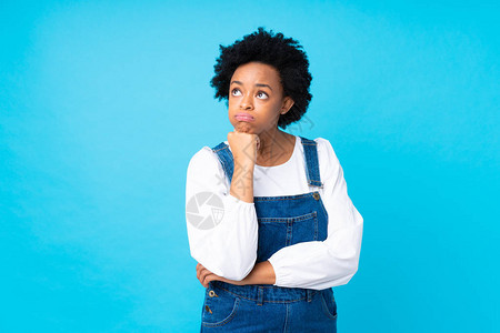 身穿长裤超过孤立蓝背景的非裔美洲妇女不快乐图片