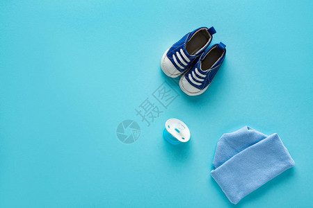 蓝底带帽子和奶嘴罩的婴儿鞋最佳视图背景图片