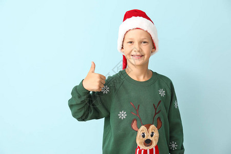 穿着圣诞毛衣和圣诞帽子的小男孩在彩色背图片