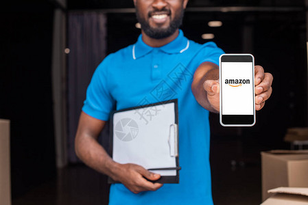 AfricanAmerican送货员带智能手机并加载Amazon页图片