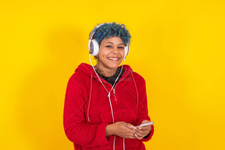 携带黄色背景移动电话和耳机的AfroAmer图片