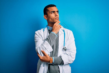身穿大衣和听诊器的非洲英俊医生男子穿着蓝色背景图片