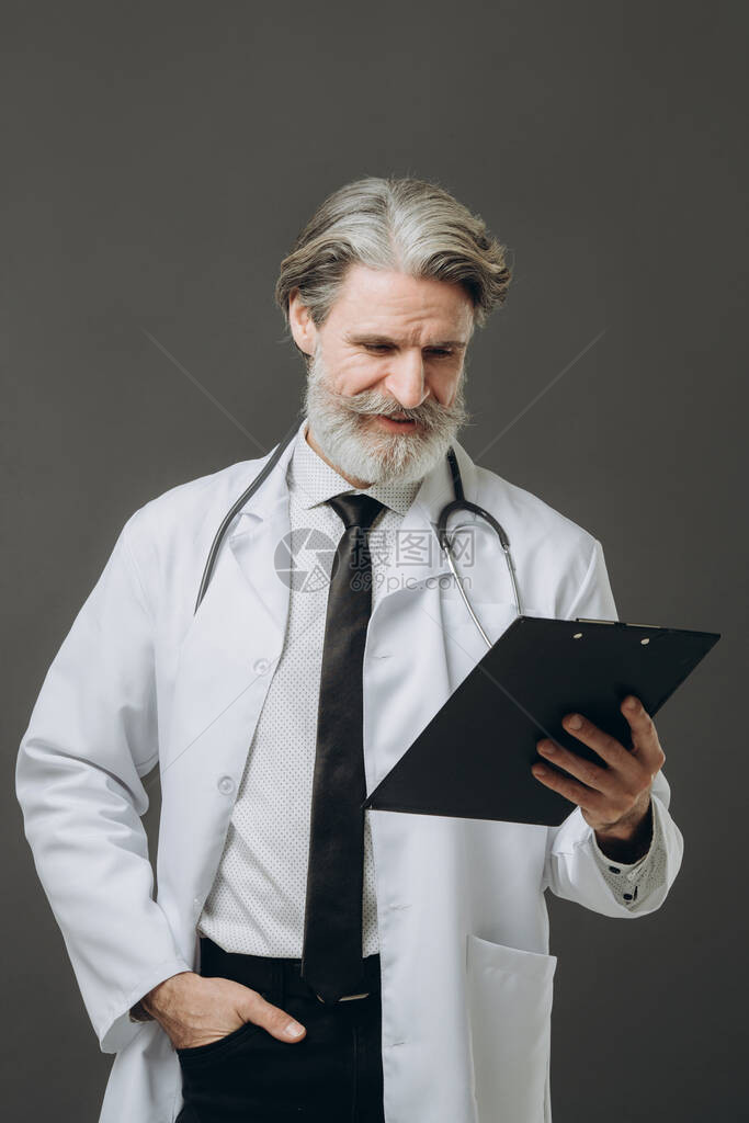 中年老医生男子在孤立的灰色背景图片