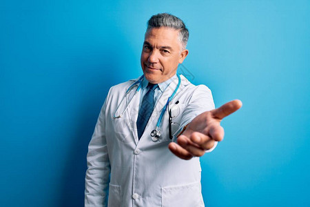 穿着大衣和蓝色听诊器的中年长英俊灰色头发的医生男子微笑着图片