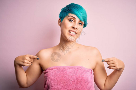 穿着蓝色时装发型的年轻女子在粉红色背景洗完澡后身着毛巾图片