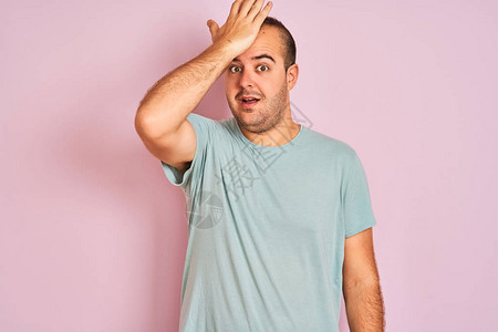 年轻人穿着蓝色休闲T恤站在孤立的粉红色背景上图片