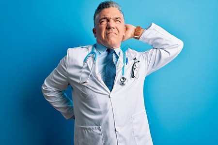 身穿大衣和蓝色听诊器的中年长英俊灰色头发医生男子图片
