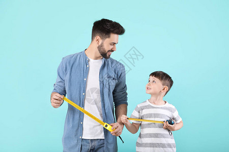 父亲和儿子在彩色背景上用卷尺图片