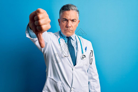 穿着大衣和蓝色听诊器的中年长英俊灰色头发的医生男子看上去不开心图片