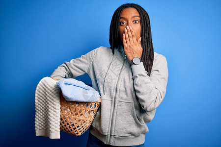 做家务的年轻非洲裔美国女孩拿着洗衣柳条篮盖嘴图片