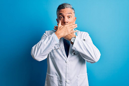穿着大衣和蓝色听诊器的中年长英俊灰色头发的医生男子因犯错误用双手图片