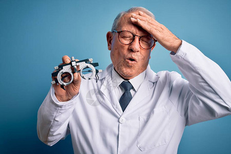 头发灰白的资深光学医生男子手持验光师眼镜图片