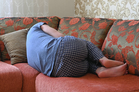 男人沮丧地躺在沙发上以胎儿的姿图片