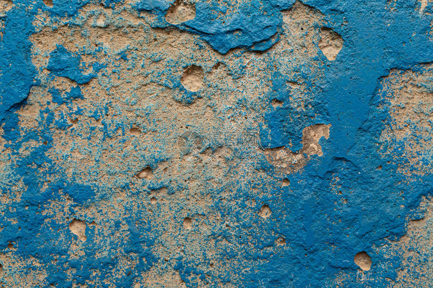 一堵粗糙的抹灰墙上面有蓝色油漆的斑点图片