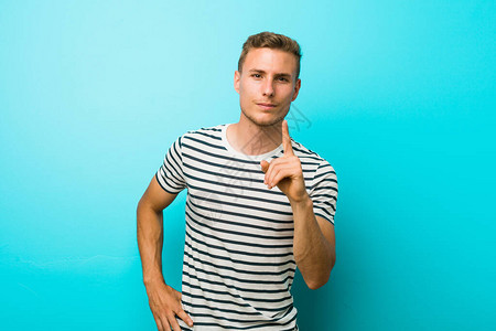年轻的caucasian男子站在蓝色的墙壁上显图片