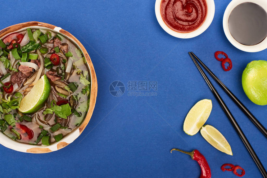 浅蓝背景的筷子石灰辣椒和酱油附图片