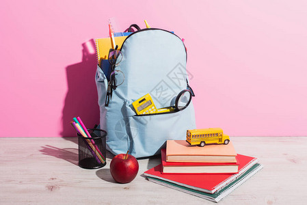 书本成熟苹果和粉红笔持有者在玩具学校巴士附近贴着文具图片
