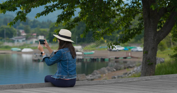 女人拍照并坐在湖边图片