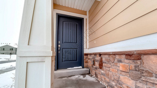 全景框盖着蓝色面板门的家庭入口和有石砖和木柴的墙壁图片