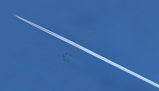 在蓝天上飞行时飞机的白色轨迹图片