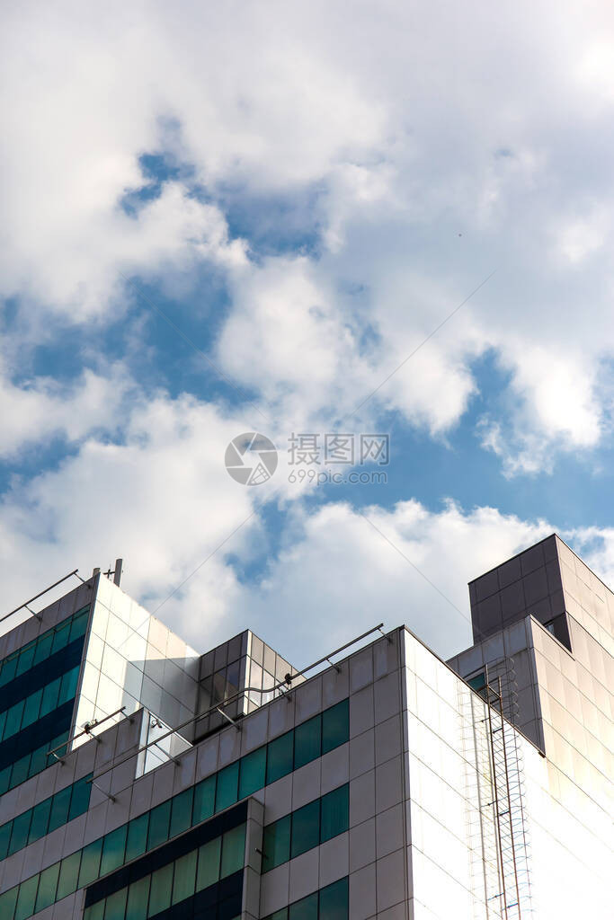 蓝天映衬下现代摩天大楼的屋顶和绿色窗户图片