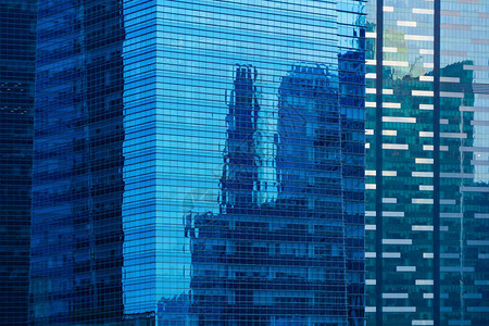 蓝色玻璃建筑立面设计与城市的天空反射图片