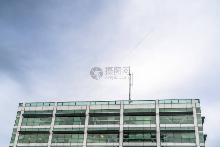 背景中带有建筑起重机的商业建筑的外观建筑物上方可以看到覆盖着白云的一图片