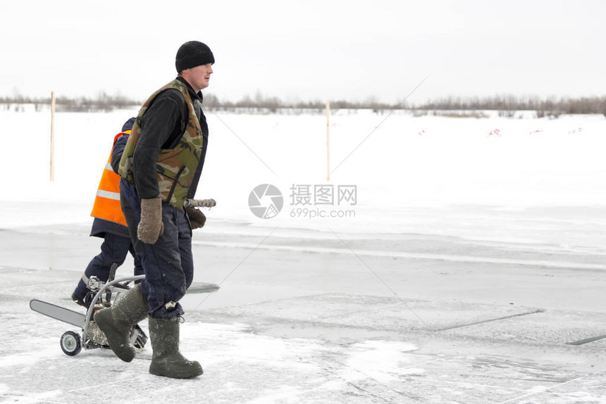 一个穿冬服的男人正在冰冻池塘的冰上行走用图片