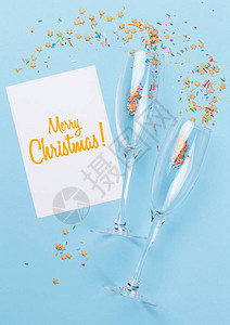 香槟杯圣诞贺卡和蓝色背景的糖果顶图片