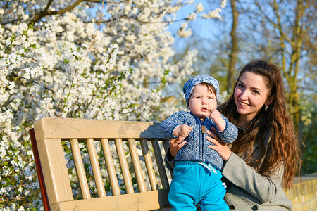 美丽的母亲与一个蓝色的小女儿在草地上坐了很长时间图片