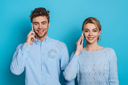 男女青年在用蓝背景的智能手机交谈时对图片