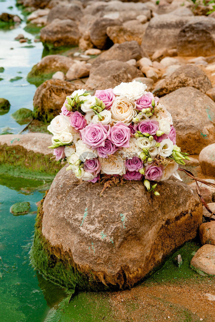 鲜花和白色玫瑰和废墟的紫白色调下的婚纱花束图片