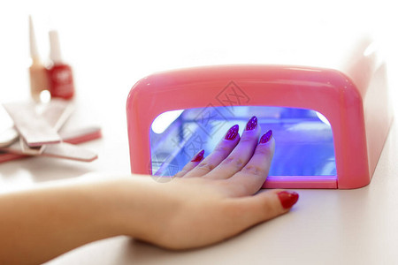 女人用紫外线灯烘干她的指甲油图片