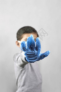 戴着医用口罩和防护手套的7岁中东男孩展示手势图片