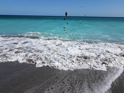 沙滩上的沙子被海浪或海浪抛向空中图片