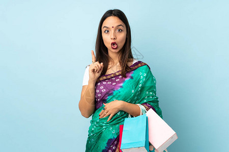 带着购物袋的年轻印度妇女想在举起一只手指的同时实现解决方图片