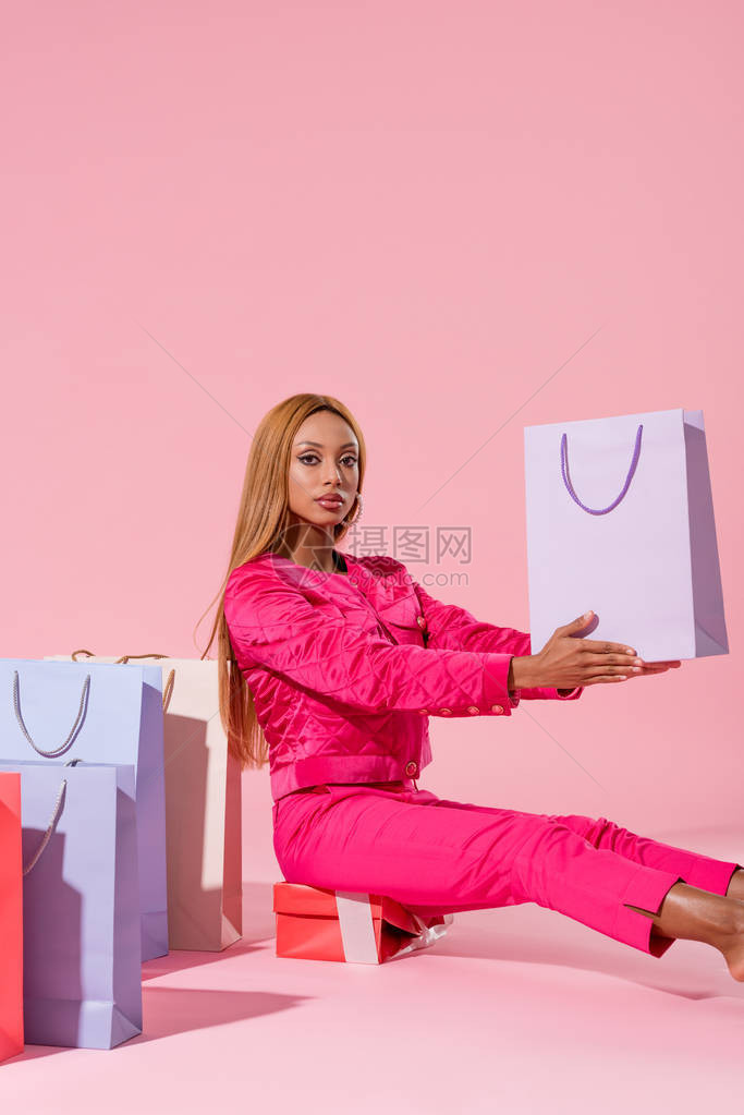 时尚女人坐在礼物盒上购物图片