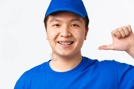 自信微笑的亚洲男快递员身穿蓝色制服的特写镜头指向自己图片