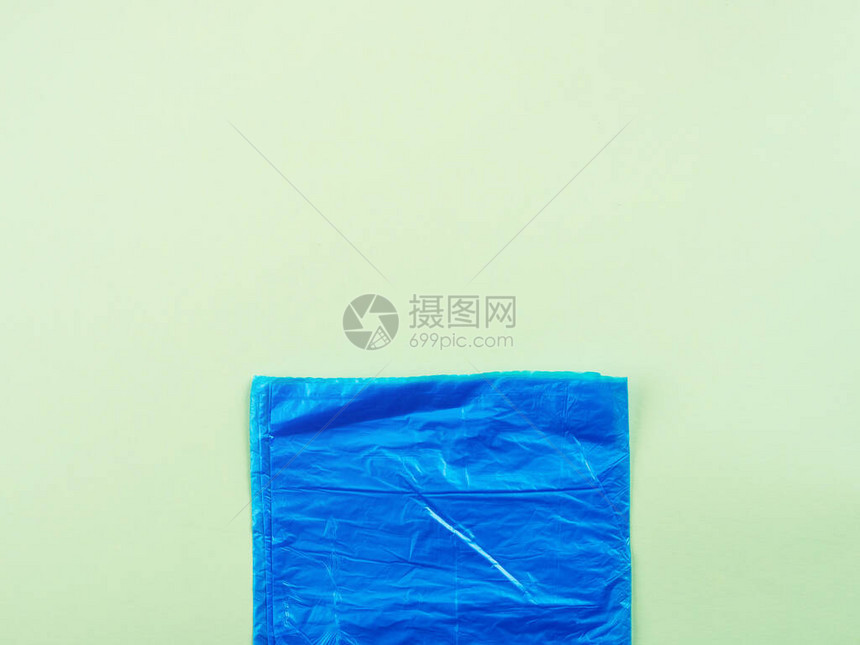 在绿色背景的蓝色塑料垃圾袋卷图片