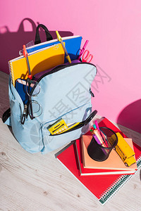 书本笔持有人和粉红色校车模型附近满学校用品的背包背包图片