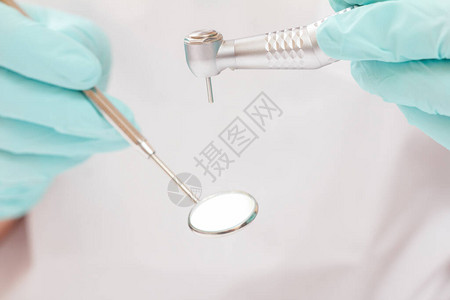 特写牙医的手在乳胶手套与口镜和高速牙科在模糊的背景医疗工具图片