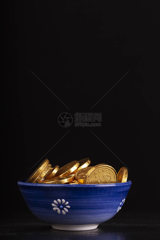 黑色背景的一锅金质硬币假巧克力钱的蓝菜富图片