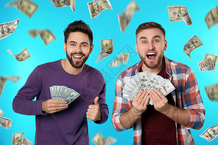 年轻快乐的男子与美元在钱雨下的金钱雨图片