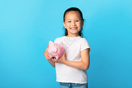 光荣的亚洲女孩拥有粉红小猪银行图片