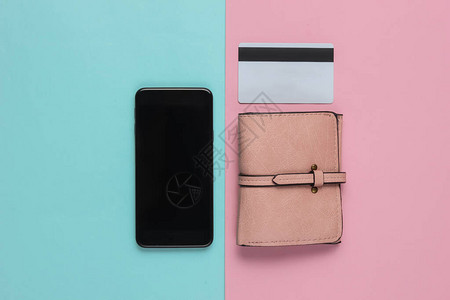 粉红色蓝面纸背景的智能手机钱包和银行卡图片