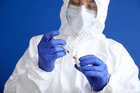 身着防护制服和有彩色背景疫苗的化验室工作人员图片