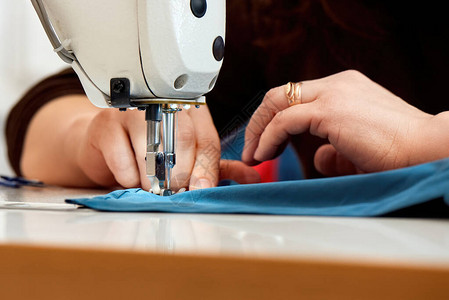 用蓝色布在缝纫机上工作的女人图片
