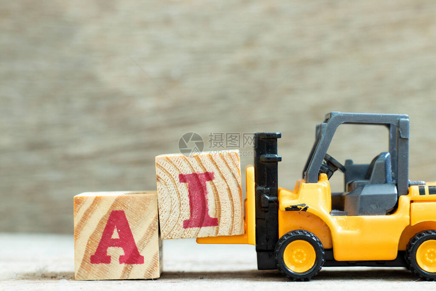玩具叉车持有字母块I以在木背景上完成单词AI图片