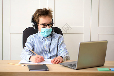 学习远程在线教育在家学习时戴医疗面具的男学生接受图片